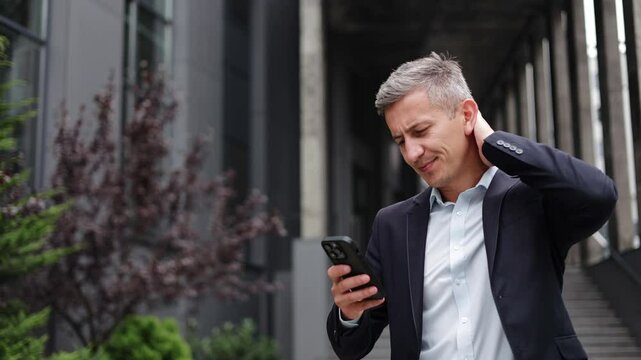 Concerned businessman gets upsetting news from his phone while on his way to a meeting. He is dressed in a suit and tie and looks very unhappy.