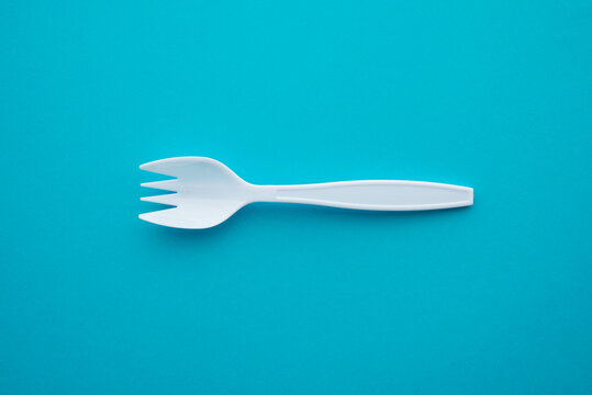 Flat lay of white plastic spork (fork plus spoon) on blue background with copy space. Abstract multi skill employee in job recruitment, HR human resource, self development, learning education concept.