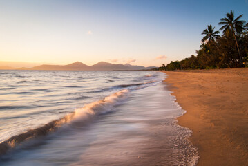 Small wave breaking onto the beach at sunset