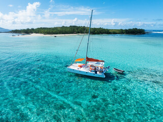 Aerial views of a catamaran in clear blue and greenish water off the coast of a tropical island. Grand Baie, Mauritius
