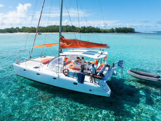 Aerial views of a catamaran in clear blue and greenish water off the coast of a tropical island. Grand Baie, Mauritius