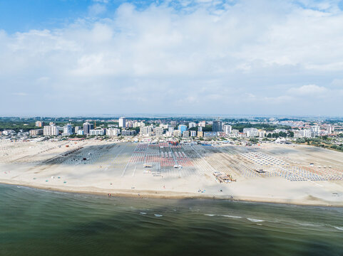 Aerial images of beach full of lounges in perfect arrangement with town in the background. Lido degli Esters, Italy