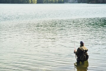 Fisher man stands in the water and catch fish in the lake on a background of mountains. High quality photo