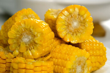 Close-up pieces of baked fresh sweet corn on plate cooked on kitchen at home. Prepare cook bake dish. Cuisine culinary nutrition domestic food recipe ingredients, organic vegetable.