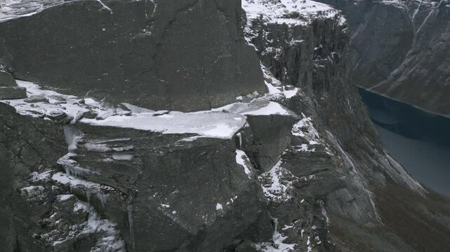 Snow-covered cliffs overlooking a fjord in the mountains of Trolltunga, Norway during winter