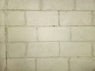 Fototapeta premium White painted bricks form a textured wall with signs of weathering and age. Old brick pattern wall texture on white