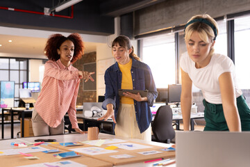 Collaborating on creative writing project, three multiracial women discussing ideas in office