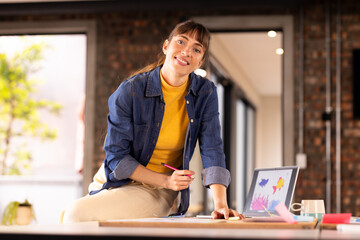 At office, Smiling woman in creative writing business, using laptop and taking notes