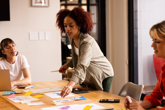 At office, Arranging notes on table, woman leading creative brainstorming session with colleagues