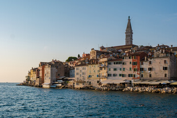 Fototapeta premium As the sun sets over Rovinj, Croatia, the vibrant colors of the waterfront buildings reflect in the calm waters, creating a picturesque view full of charm and history