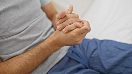 A young hispanic man relaxes in a bedroom, highlighting tranquility and wellbeing in a home setting.