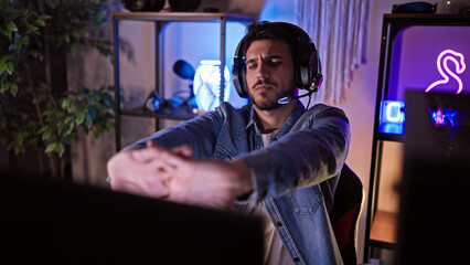 A young hispanic man stretches during a break in a neon-lit gaming room at night © Krakenimages.com