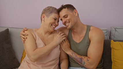Mother and son sitting close together smiling showing love and happiness in a cozy living room with...