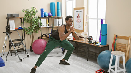 Fototapeta premium Young adult african american man exercising in a rehabilitation clinic's workout room