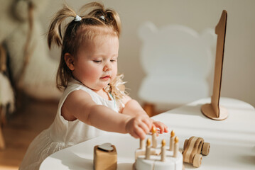 Cute beautiful girl baby staying on the floor in the children's room and playing in eco wooden toys...