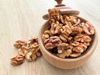 walnuts spill out of a wooden plate on a black table.