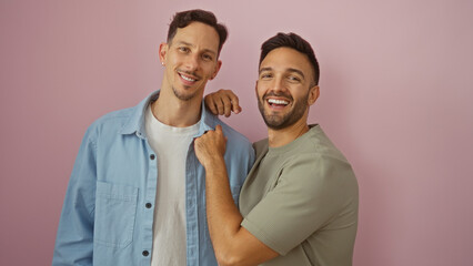 Loving gay couple smiling warmly while standing close against a pink background, conveying unity...