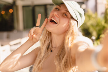 Happy woman using smartphone at cafe. Smiling blonde woman using smart phone make selfie, spends...