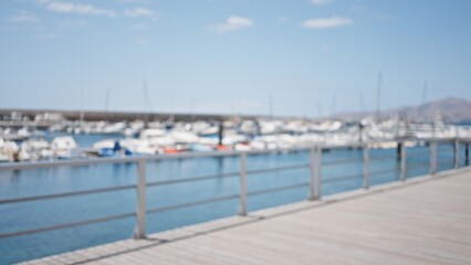 Defocused view of marina with yachts in background and blurred pier railing under a bright sunny sky