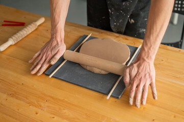 Close-up of potter's hands rolling out clay. 