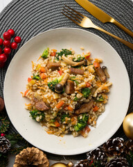 Rice paella with pork loin, mushrooms and broccoli. Top view table with christmas decoration.