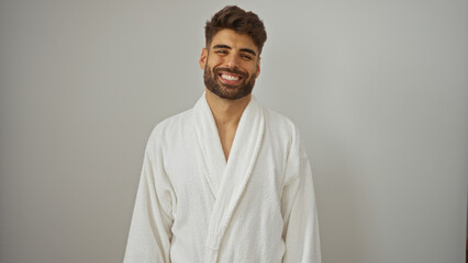 Handsome bearded young man in a white bathrobe smiling warmly against an isolated white background