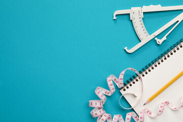 Body fat caliper, measuring tape, notebook and pencil on light blue background, flat lay. Space for text