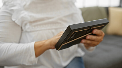 A middle-aged woman examines a photo at home, evoking themes of memory and nostalgia.