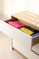 Chest of drawers with different folded clothes, closeup