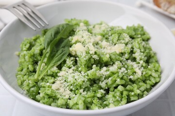 Delicious spinach risotto with parmesan cheese served on white tiled table, closeup