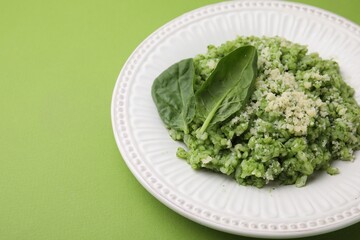 Tasty spinach risotto on light green background, closeup. Space for text