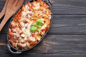 Delicious al forno pasta in baking dish on wooden table, top view. Space for text