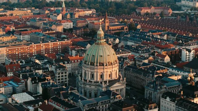 Aerial view of Frederiks Kirke in Copenhagen, Denmark, circling right at close range showcasing the dome's architecture at sunset