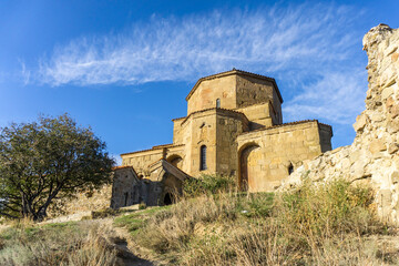 Obraz premium Jvari Monastery close view. Ruins of the tower and fortress wall. Green grass, bright blue sky