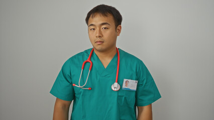 Young, handsome chinese male doctor in green scrubs with a red stethoscope isolated against a white background wall.