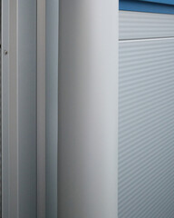 View of a white gutter leaning against white aluminum building siding