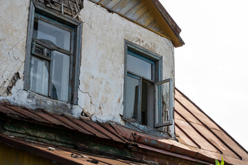 An aged building characterized by a rusty roof and shattered windows
