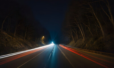 Cars driving on a forest road at night with light trails