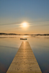 Fototapeta premium Wooden jetty in the morning at sunrise in the fog, on a Swedish lake. Scandinavian