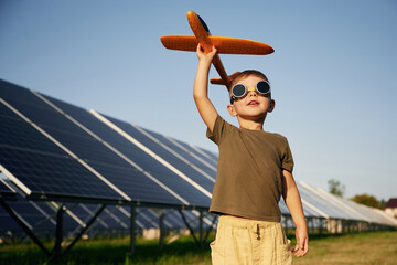 Time to fly. Aviator glasses and toy plane. Little boy is with solar panels outdoors