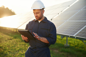 Reflection of the sunlight behind. Man is working with solar panels outdoors at daytime