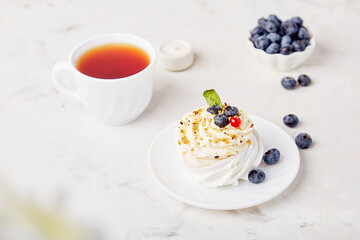 Traditional Pavlova Dessert with Tea Cup and blueberry. Autumn tea time vibes background. Hygge aesthetics