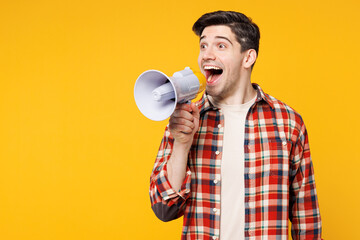 Young happy man wears red checkered shirt casual clothes hold in hand megaphone scream announces discounts sale Hurry up isolated on plain yellow orange background studio portrait. Lifestyle concept.