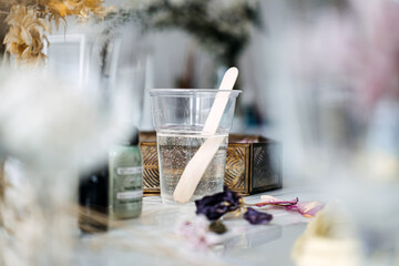 Resin mixing in a clear plastic cup with wooden stir stick, surrounded by dried flowers and...