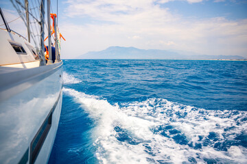 Yacht sailing in an open sea. Close-up view of side of the boat. Clear sky after the rain, waves...