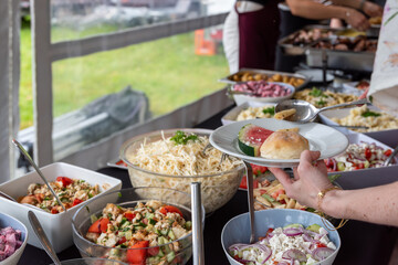 Wedding guests serving themselves various dishes at outdoor buffet, Buffet table with food, catering food wedding buffet event