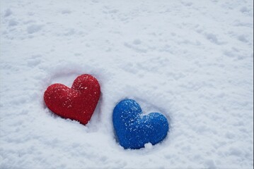 Fototapeta premium Red and blue heart-shaped objects on snow