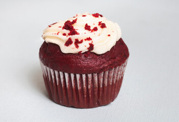 Single red velvet cupcake on light pastel blue with selective focus and copy space