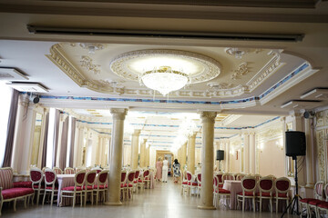 A large festive hall in the restaurant with tables and chairs.