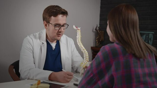 An experienced doctor, osteopath, conducts consultations in a modern clinic. A man consults a patient. The MRI image is open on the computer screen.